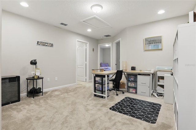 office space with attic access, visible vents, a textured ceiling, and light colored carpet