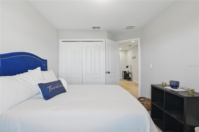 bedroom featuring carpet, a textured ceiling, visible vents, and a closet