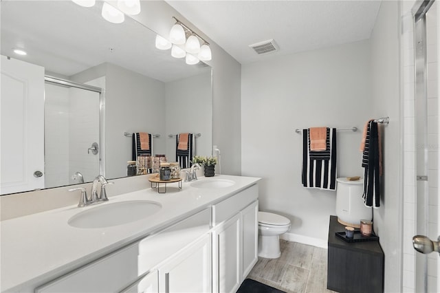 bathroom with a stall shower, visible vents, a sink, and wood finish floors