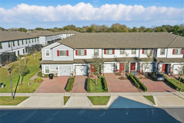 view of property featuring an attached garage, driveway, a residential view, and a front yard