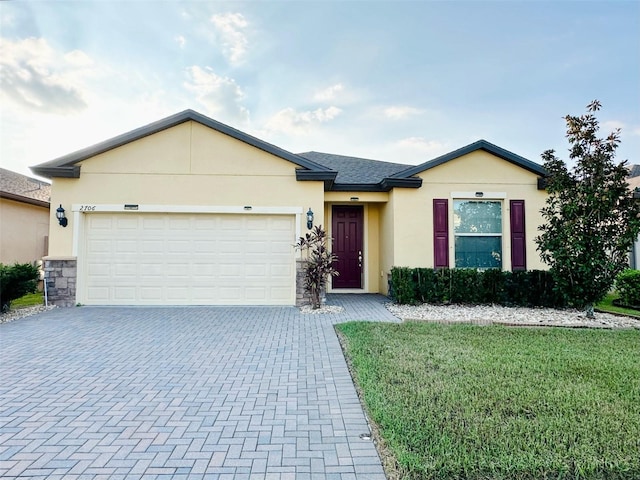 ranch-style home with decorative driveway, stucco siding, a shingled roof, an attached garage, and a front yard