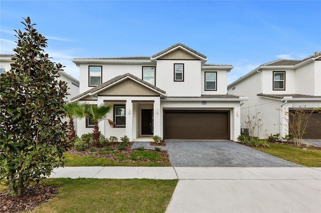 traditional home featuring decorative driveway, an attached garage, and stucco siding