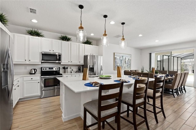 kitchen with wood finish floors, visible vents, white cabinetry, light countertops, and appliances with stainless steel finishes