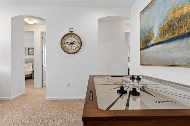 interior space with arched walkways, carpet flooring, and baseboards