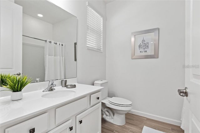 full bathroom with toilet, a shower with shower curtain, wood finished floors, vanity, and baseboards