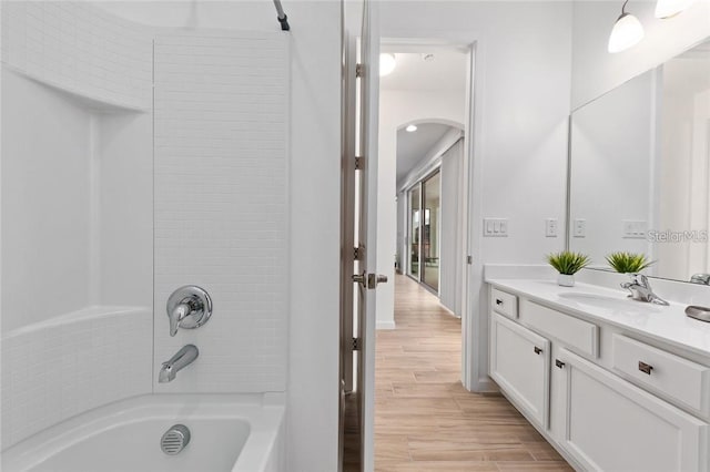 full bath with washtub / shower combination, vanity, baseboards, and wood finished floors