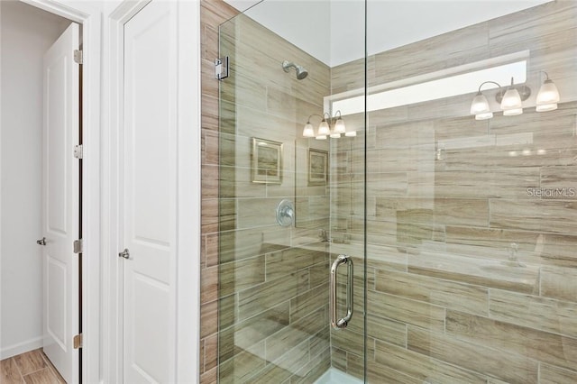 full bathroom with a stall shower, wood finished floors, and an inviting chandelier