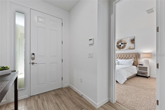 foyer with baseboards, visible vents, and wood finished floors