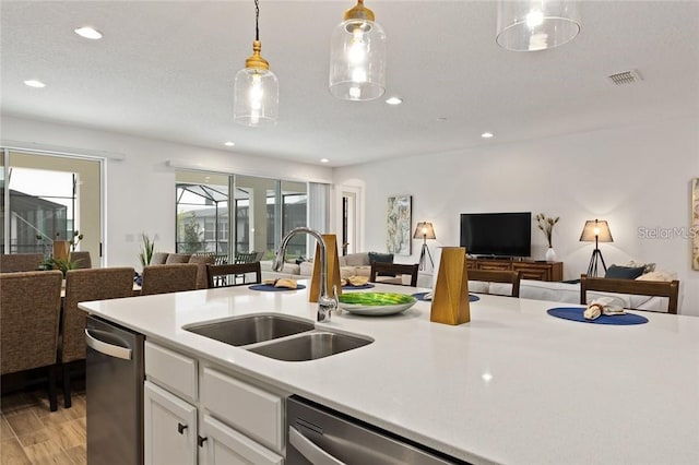 kitchen with stainless steel dishwasher, open floor plan, a sink, and light countertops