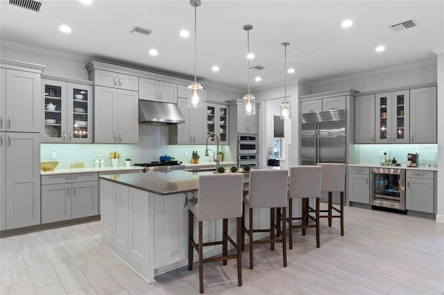 kitchen featuring wine cooler, gray cabinets, visible vents, and under cabinet range hood