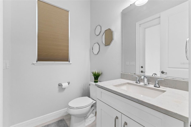 bathroom with baseboards, vanity, and toilet