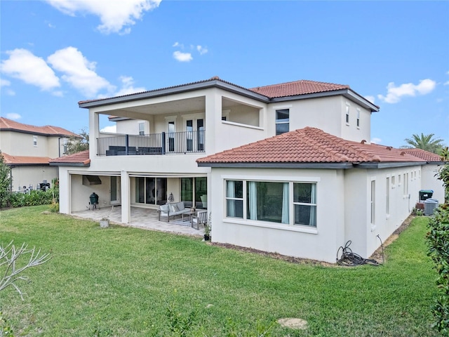 back of property featuring a lawn, a patio area, a balcony, and stucco siding