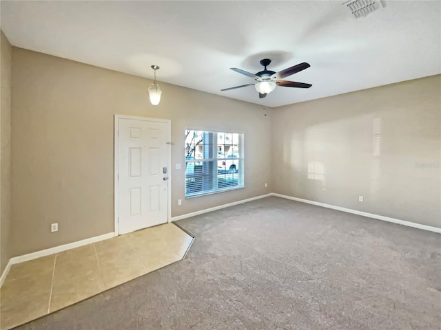 interior space featuring ceiling fan, carpet flooring, visible vents, baseboards, and tile patterned floors