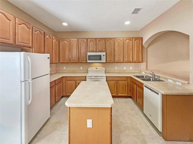 kitchen with light tile patterned floors, white appliances, a kitchen island, and a sink