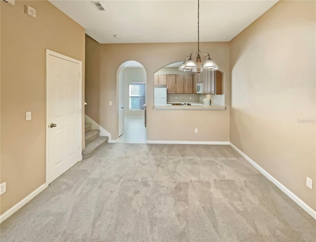 unfurnished living room with baseboards, visible vents, a notable chandelier, and light colored carpet