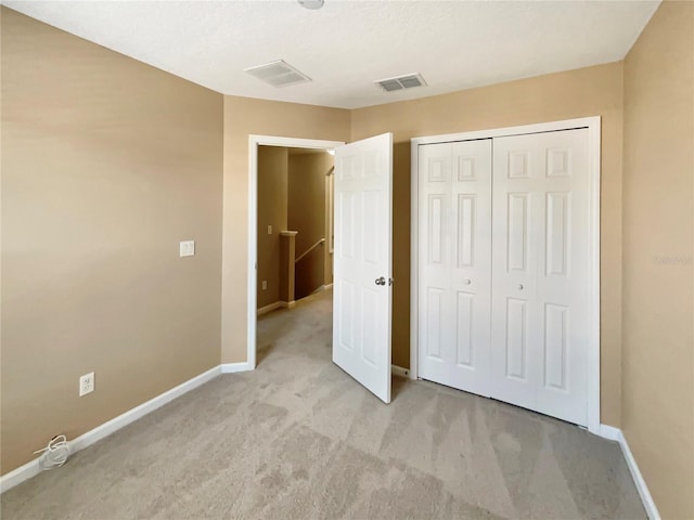 unfurnished bedroom featuring a closet, light carpet, visible vents, and baseboards