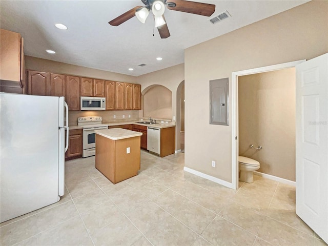 kitchen featuring arched walkways, light countertops, visible vents, white appliances, and electric panel