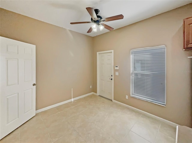 spare room featuring light tile patterned floors, ceiling fan, and baseboards