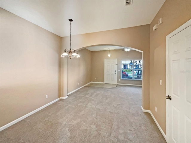 carpeted empty room with arched walkways, ceiling fan with notable chandelier, visible vents, and baseboards