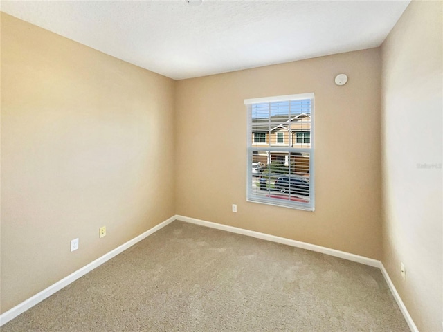 spare room with baseboards and carpet flooring