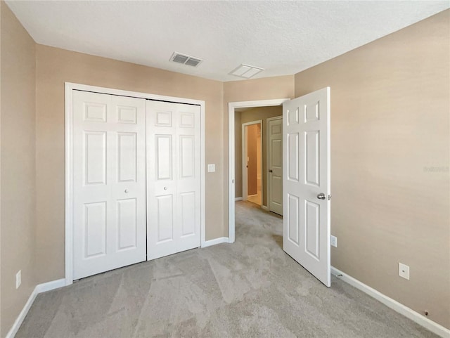 unfurnished bedroom featuring baseboards, visible vents, a closet, and light colored carpet