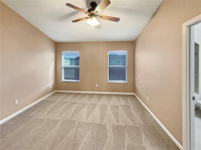 carpeted empty room featuring ceiling fan and baseboards