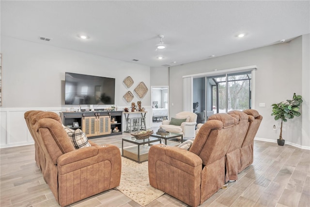 living area with light wood finished floors, visible vents, recessed lighting, and a wainscoted wall