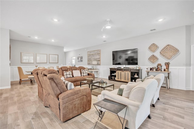 living room with visible vents, wood tiled floor, recessed lighting, wainscoting, and a decorative wall