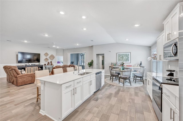 kitchen with light countertops, a center island with sink, appliances with stainless steel finishes, and a sink