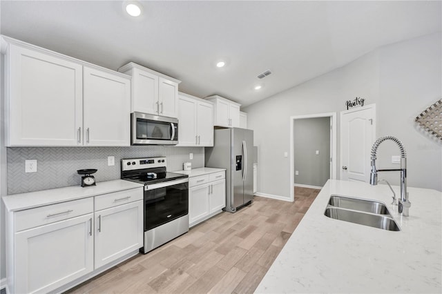 kitchen with visible vents, lofted ceiling, a sink, stainless steel appliances, and backsplash