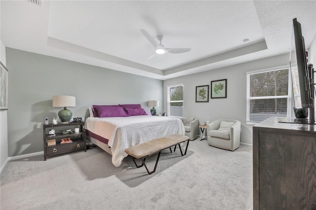 bedroom with ceiling fan, baseboards, a tray ceiling, and carpet floors