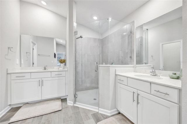 full bathroom featuring two vanities, a stall shower, and a sink