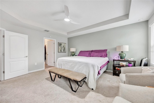 carpeted bedroom featuring visible vents, a raised ceiling, baseboards, and a ceiling fan