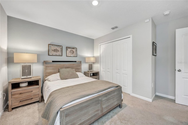 carpeted bedroom with visible vents, baseboards, and a closet