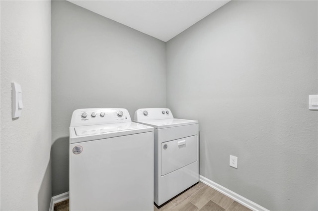 laundry room with baseboards, light wood-style flooring, laundry area, and washer and clothes dryer