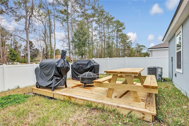 wooden terrace with central AC unit, a grill, a fire pit, and a fenced backyard