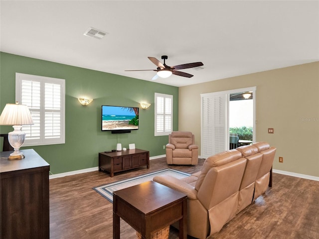 living room featuring baseboards, visible vents, ceiling fan, and wood finished floors