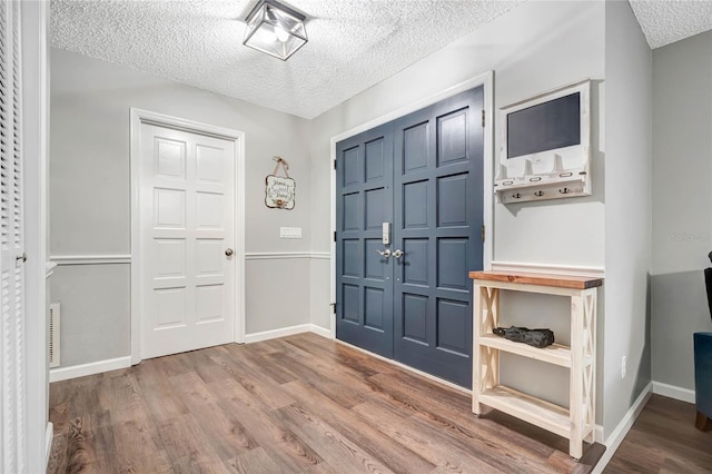 entryway featuring a textured ceiling, baseboards, and wood finished floors