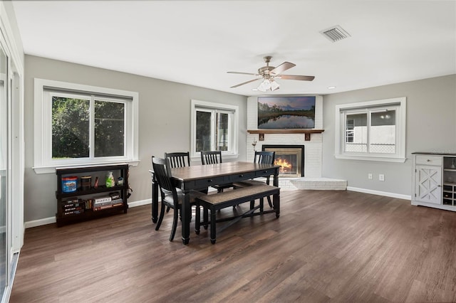 dining space with a brick fireplace, dark wood finished floors, and baseboards