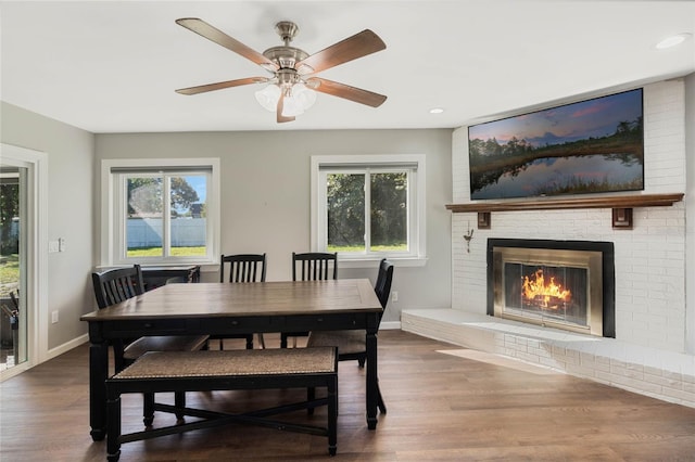 dining room with a healthy amount of sunlight, a fireplace, baseboards, and wood finished floors