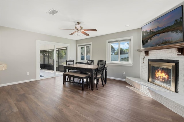 dining space featuring visible vents, a fireplace, baseboards, and wood finished floors