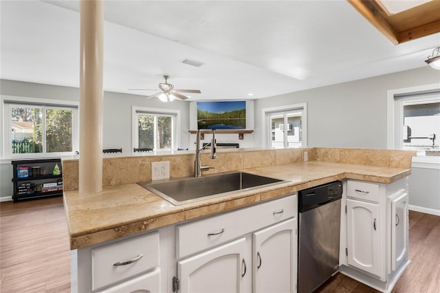 kitchen featuring visible vents, stainless steel dishwasher, white cabinetry, a sink, and wood finished floors