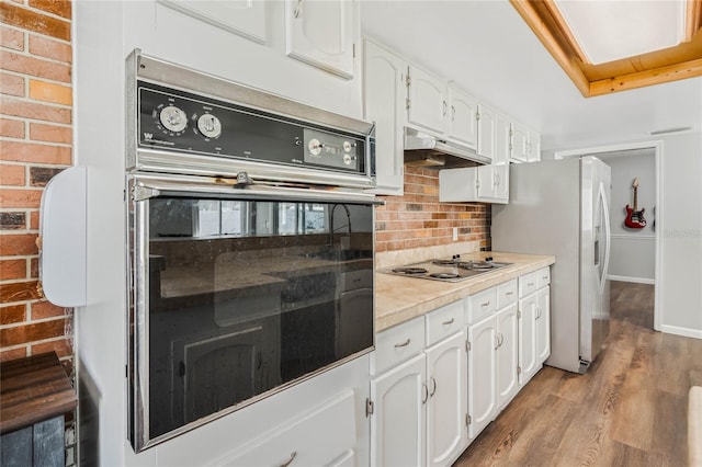 kitchen featuring white cabinetry, decorative backsplash, oven, and under cabinet range hood