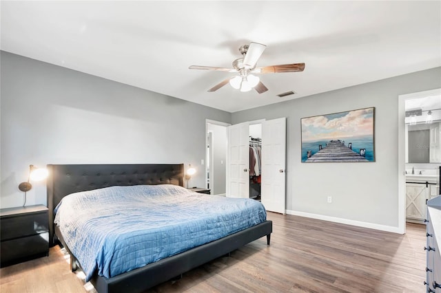 bedroom featuring wood finished floors, visible vents, baseboards, a closet, and a walk in closet