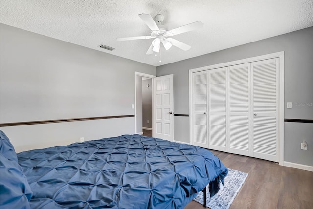 bedroom featuring ceiling fan, a textured ceiling, visible vents, and wood finished floors