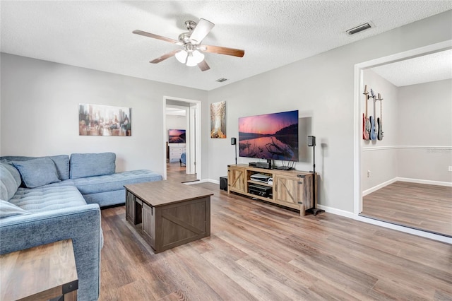 living area featuring wood finished floors, visible vents, and a ceiling fan