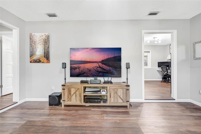 living room with baseboards, a textured ceiling, visible vents, and wood finished floors