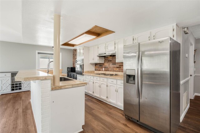 kitchen with dark wood-style floors, appliances with stainless steel finishes, white cabinets, a sink, and under cabinet range hood