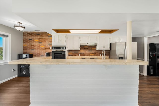 kitchen featuring under cabinet range hood, dark wood-style flooring, white cabinetry, light countertops, and appliances with stainless steel finishes