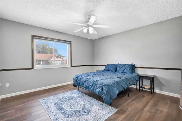 bedroom featuring ceiling fan, a textured ceiling, baseboards, and wood finished floors